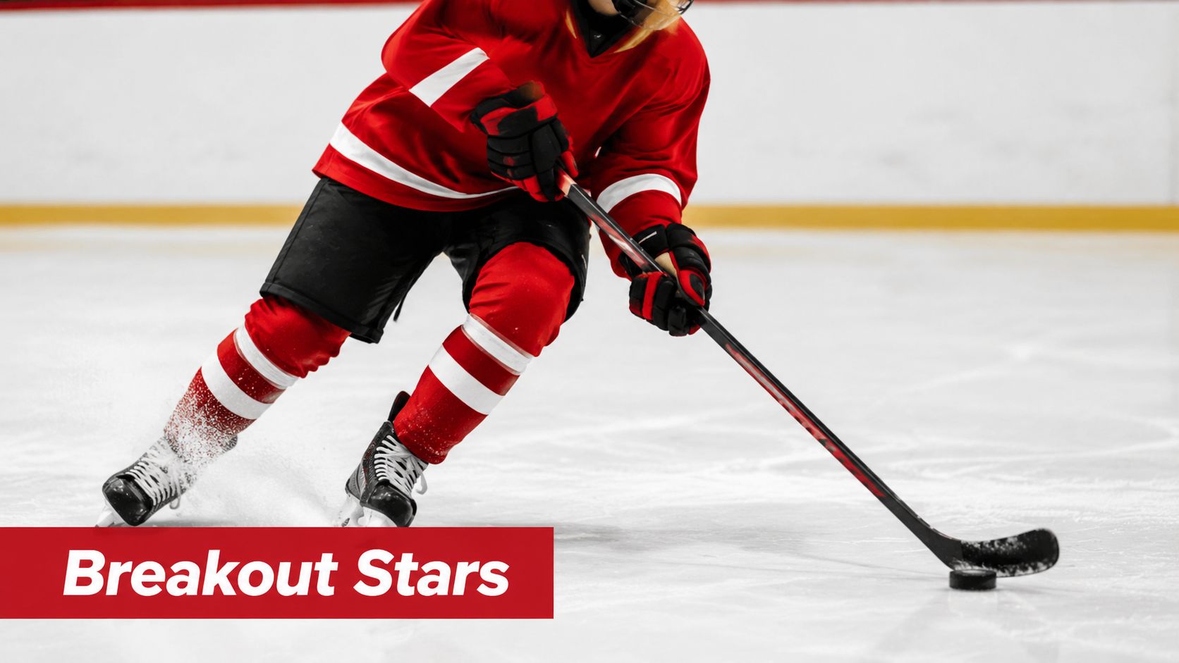 A hockey player in a red jersey skating across the ice with a puck and stick.