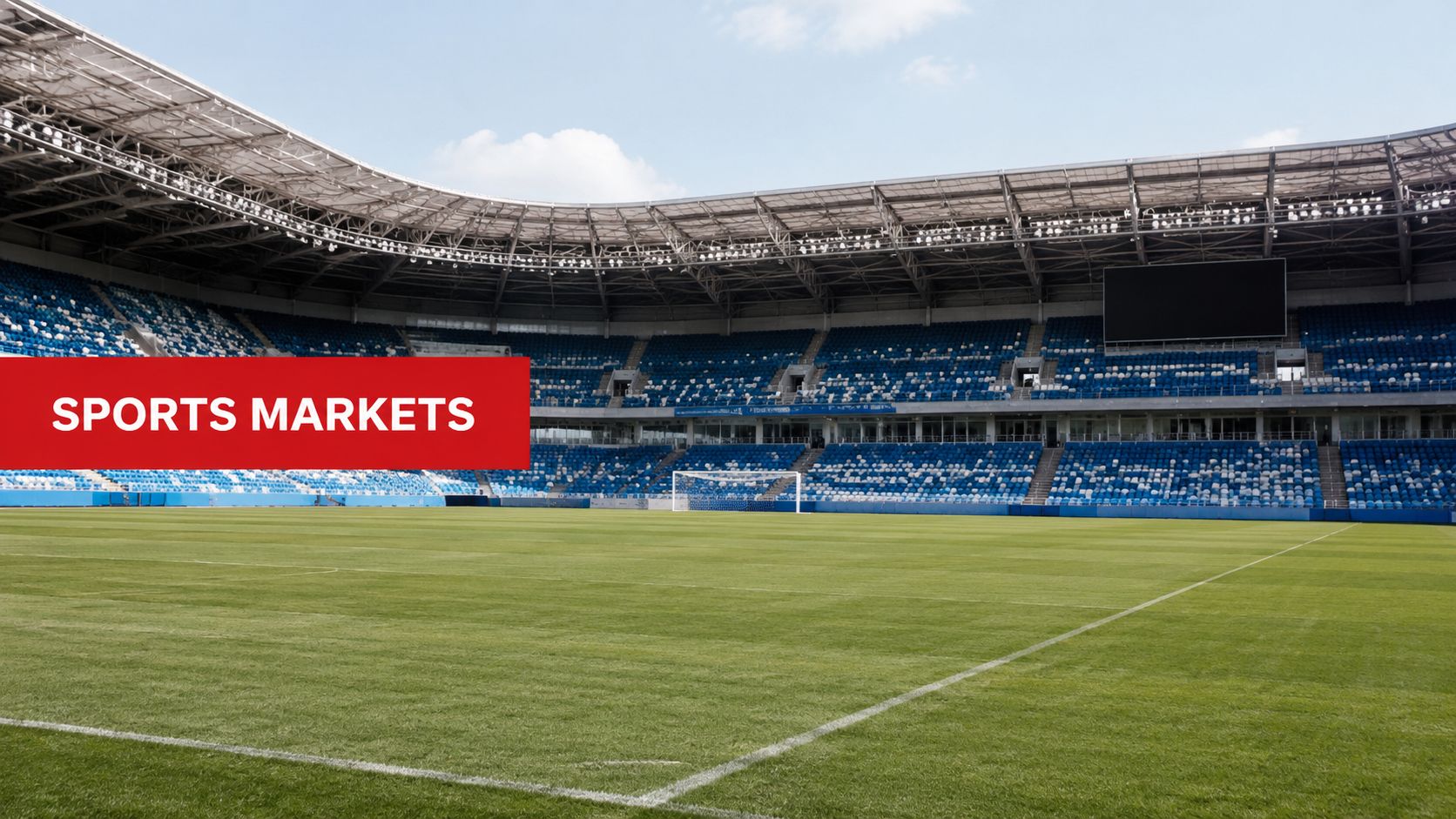 A wide angle view of an empty professional soccer stadium with blue seating and green grass.